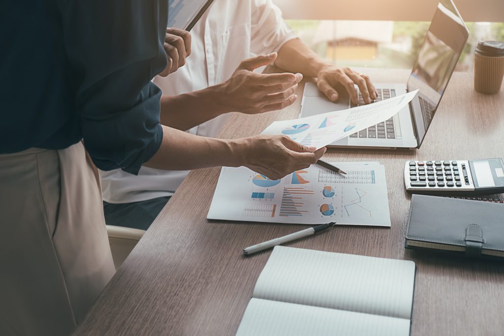 Implementing a successful pAOOH campaign requires a blend of creative content development, strategic planning, and technological integration - coworkers discussing marketing charts/reports at desk