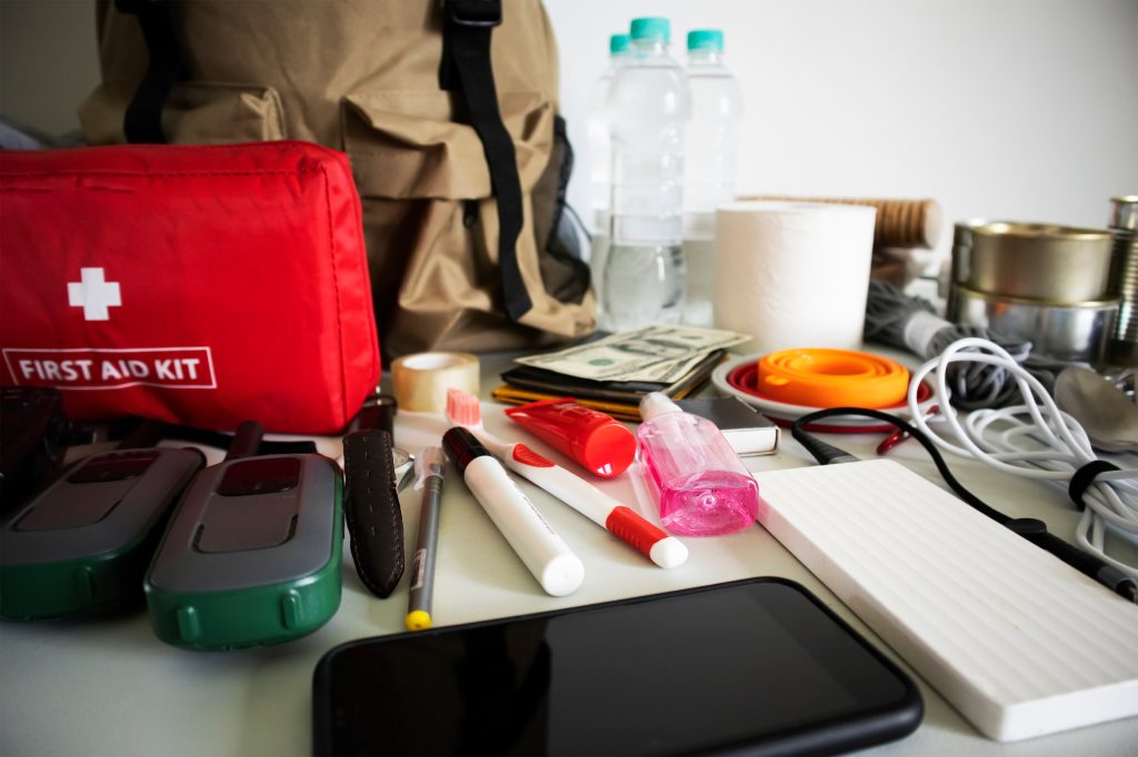 Emergency backpack equipment organized on the table. Documents, water,food, first aid kit and another items needed to survive  - Best Practices for Customized Audio in Summer Emergencies