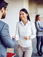 1. You're Hiring, but Your System Isn't Scaling - Signs your business has outgrown its phone system - Smiling new employee shakes hand and is introduced to staff in office setting showing the need for tech updates with growing businesses.